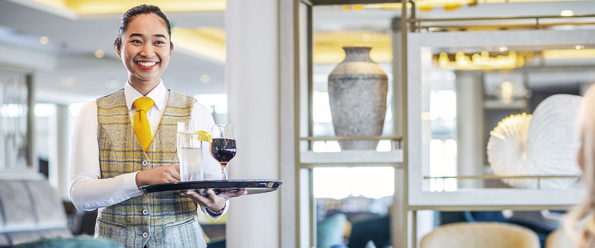 A waitress serving drinks in the Britannia Lounge on Spirit of Adventure